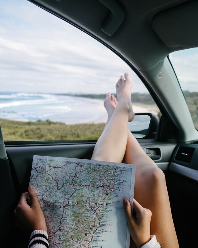 woman inside car reading travel map